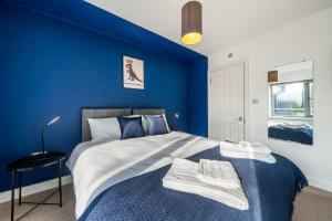 a blue bedroom with a king sized bed with blue walls at Modern Apartment In Central Watford by Hampton - Ideal For Professionals & Contractors in Watford