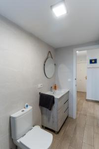 y baño con aseo, lavabo y espejo. en Apartamento Torre Cervantes, moderno, luminoso, a 5 min de la Playa, en Almería