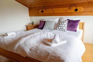 a bedroom with a large white bed with purple pillows at S.A.W. Rooms in Schiefling am See