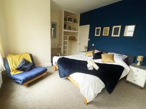 um quarto com uma cama grande e uma parede azul em Private 7 bed wing of former farmhouse, edge of Exmoor, sleeps 16 em East Anstey