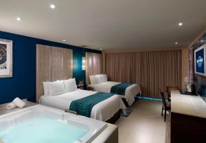 a hotel room with two beds and a bath tub at Hard Rock Hotel Cancun - All Inclusive in Cancún