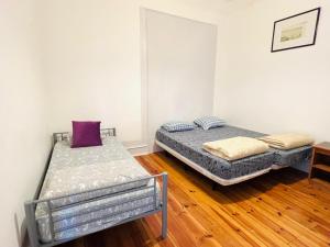 two beds in a room with wooden floors at Fortune Guest house in Lisbon