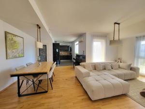 Jana Vienna Airport Apartment في سخويشات: غرفة معيشة مع أريكة بيضاء وطاولة خشبية