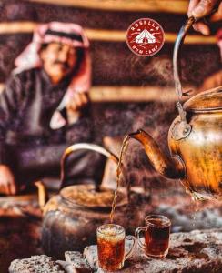 a teapot pouring tea into two glasses on a table at Rosella rum camp in Wadi Rum