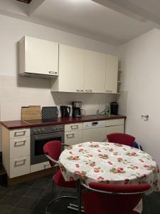 a kitchen with a table with red chairs and a kitchen with white cabinets at Großes 2-Schlafzimmer Apartment in Cölbe in Cölbe