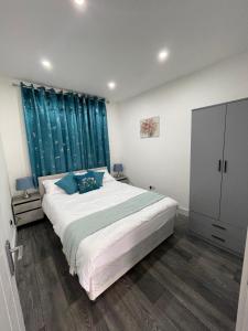 a bedroom with a large bed with blue curtains at Private One Bedroom Flat in Barnet, London in Finchley