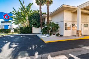 een parkeerplaats voor een gebouw met palmbomen bij Motel 6-Anaheim, CA in Anaheim