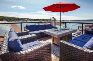 une terrasse avec des canapés et une table avec un parasol dans l'établissement Tugboat Inn, à Boothbay Harbor