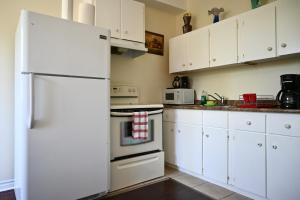 a kitchen with white cabinets and a white refrigerator at Centennial Suite in Niagara Falls