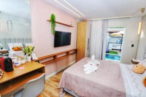 a room with a bed and a desk and a television at Villa Beija-Flor2: Suíte alexa e piscina privativa in Japaratinga