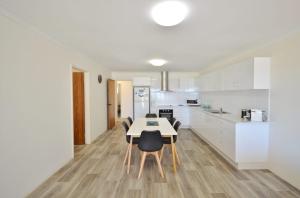 a kitchen with white cabinets and a table and chairs at Kalbarri Waters A - Kalbarri WA in Kalbarri