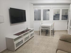 a living room with a table and a television on a wall at O RECUNCHO DE MORA in Ribeira