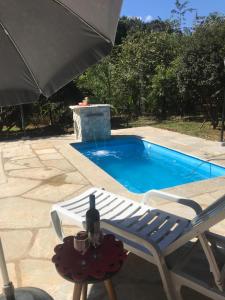 a chair and a bottle of wine on a table next to a pool at Chalé Veredas e Buritis in Pirenópolis