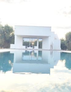 una casa bianca con una piscina di fronte di Olive trees house a Torre Canne