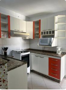 a kitchen with white cabinets and a stove top oven at Casa aconchegante no centro in Divinópolis +5 photos
