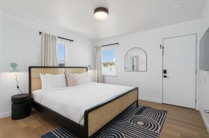 a white bedroom with a large bed and a rug at Aliza Hotel in Los Angeles