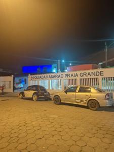 dois carros estacionados num parque de estacionamento à noite em Pousada Kasarão Praia Grande Ubatuba em Ubatuba