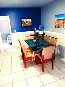 uma mesa de jantar com cadeiras e uma parede azul em Recanto Munik em Palhoça