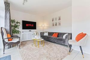 ein Wohnzimmer mit einem Sofa und einem TV in der Unterkunft Luxury Modern House - 8 mins to NEC, Airport in Birmingham