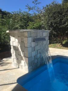 a water fountain in a stone wall next to a swimming pool at Chalé Veredas e Buritis in Pirenópolis