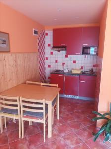 オストラヴァにあるMAT ubytováníのキッチン(赤いキャビネット、木製テーブル、椅子付)