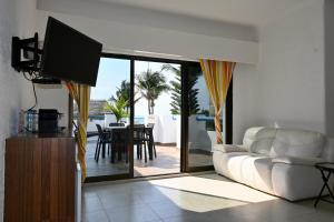 a living room with a white couch and a television at Pelicano Inn Playa del Carmen - Beachfront Hotel in Playa del Carmen