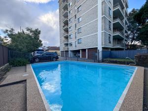 a large blue swimming pool in front of a building at Large 1-Bed with Swimming Pool in Iconic Bondi in Sydney