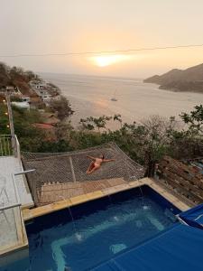 a man jumping into a swimming pool with a view of the ocean at Tayrona Colors Hostel in Taganga