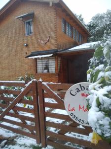 una casa con una puerta de madera en la nieve en CABAÑA LA MATILDE en Río Ceballos