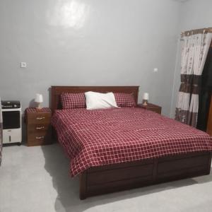 1 dormitorio con 1 cama con manta de cuadros roja en The Balbina House, en Labuan Bajo