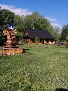 ein Holzhaus mit einer Statue vor einem Feld in der Unterkunft Stara Khata Карпати in Scheschory