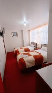 a hotel room with three beds with red carpet at Ayma Hostel Puno in Puno