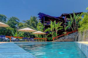 a swimming pool with umbrellas and a resort at Chocolate Hotel in Itacaré