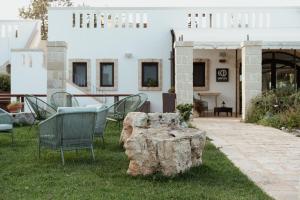 a group of chairs and a rock in the grass at Oppure - Masseria Moderna in Polignano a Mare