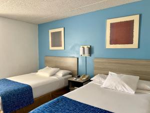 two beds in a hotel room with blue walls at Travelodge by Wyndham Hershey in Hershey