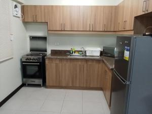 a kitchen with wooden cabinets and a stainless steel refrigerator at Asteria Lovely Staycation in Manila