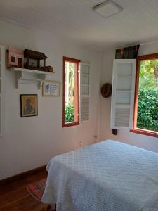 1 dormitorio con 1 cama y 2 ventanas en Pousada Casa das Fontes, en Tiradentes