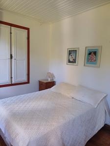 1 dormitorio con cama blanca y ventana en Pousada Casa das Fontes, en Tiradentes