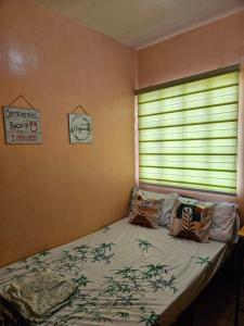 Un dormitorio con una cama y una ventana con una persiana en Mel's Place 2BR Apartment Unit2 in Batangas City, en Batangas