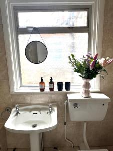 een badkamer met een wastafel en een raam met bloemen bij Charming, Renovated Residence in Willesden Green in Londen