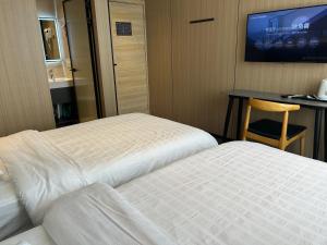 a hotel room with two beds and a table and a tv at Jingdezhen International Youth Hostel in Jingdezhen