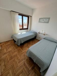2 camas num quarto com pisos em madeira e uma janela em Bolivar y Guemes. Vista al mar. em Mar del Plata