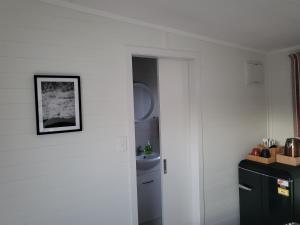 a kitchen with white walls and a black refrigerator at TradeStop Short-Term Accomodation in Raglan