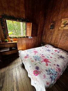 a bedroom with a bed with a flowered blanket at Hostel Rústico MarAbi in Tárcoles