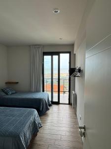 a bedroom with two beds and a door to a balcony at Liniers, con vista al mar in Mar del Plata