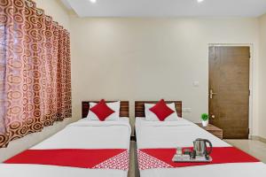 two beds with red pillows in a room at OYO Coastal Inn near JNTU College in Kākināda