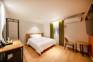 1 dormitorio con cama blanca, mesa y silla en Hound Hotel Gumi indong, en Gumi