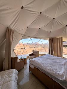 a bedroom with a bed and a large window at Jabal Rum Camp in Wadi Rum