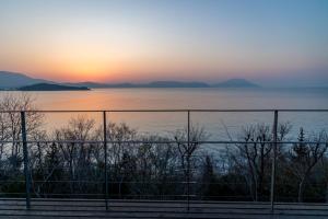 a view of the ocean at sunset behind a fence at 千年オリーブテラス for your wellness 「The STAY」 in Tonosho +55 photos