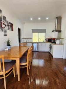 a kitchen and dining room with a wooden table and chairs at LUXURIOUS Couples Escape, SPA BATH, Netflix, NBN in Victor Harbor